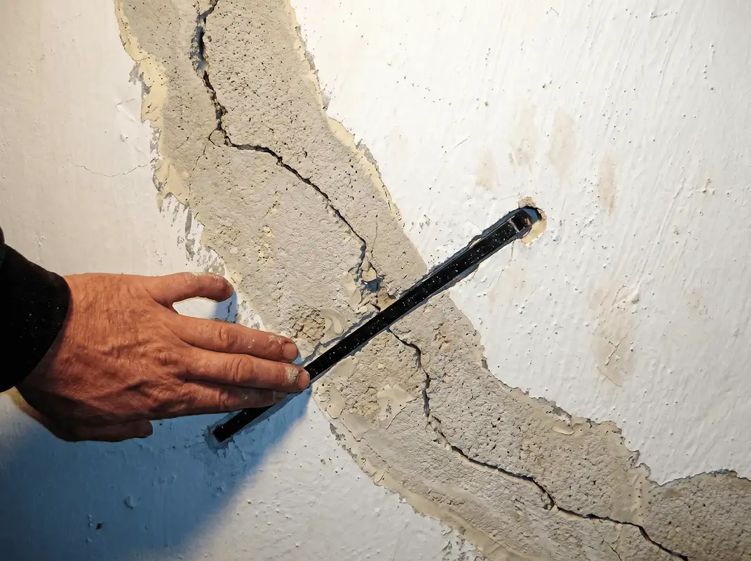 A wall with a large crack is being inspected by a professional in Richmond, VA