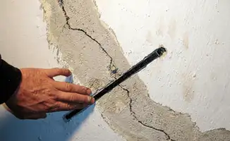 A wall with a large crack is being inspected by a professional in Richmond, VA
